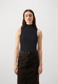 Schwarzes, ärmelloses Top mit hohem Kragen, kombiniert mit einem dunkelbraunen Jeans-Bleistiftrock. Die Stoffe sind glatt, eng anliegend und weisen dezente Strukturen auf.
