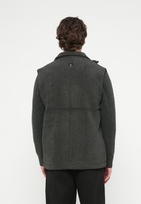 Donkergroene fleece-vest met een gestructureerd oppervlak, kraag en schouderdetails. Heeft een klein zwart logolabel aan de achterkant.