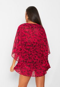 Kimono trasparente e leggero in vivace fucsia con un motivo floreale nero. Vestibilità ampia con maniche larghe e orlo curvo.