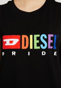 T-shirt noir avec le logo coloré "DIESEL" aux couleurs de l'arc-en-ciel et le texte blanc "PRIDE" sous le logo, au niveau de la poitrine.