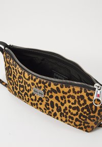 Sac à main en imprimé léopard avec un extérieur texturé et pelucheux. Dispose d'un intérieur noir, d'une fermeture éclair et d'un accent en matériel argenté.