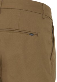 Brown trousers feature a smooth texture, a back pocket with a horizontal seam, and a small tag reading "CASUAL."