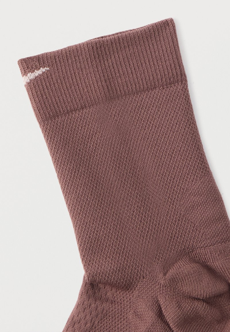 Brown knitted sock with a ribbed cuff, featuring a textured pattern and a white stripe at the top. Soft material, designed for comfort.