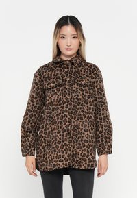 Giacca camicia con stampa leopardata realizzata in tessuto morbido e testurizzato, con colletto, chiusura frontale con bottoni e due tasche sul petto.