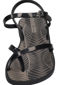 Black plastic sandal with a crisscross strap design, featuring a textured gray insole with a leaf pattern. Adjustable buckle on the strap.