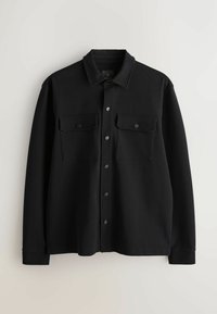 Schwarzes Hemd mit Knopfleiste aus strukturiertem Stoff. Verfügt über zwei Brusttaschen, einen Kragen und schwarze Druckknöpfe. Lange Ärmel.