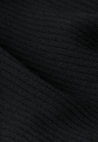 Tessuto nero lavorato a maglia con una trama a coste, che mette in mostra una superficie morbida e liscia e leggere variazioni nella densità del filo e nella finitura.