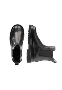 Bottes noires en cuir à chevilles avec une finition lisse, des panneaux latéraux élastiques et un motif texturé sur le talon. Semelle épaisse à rainures.