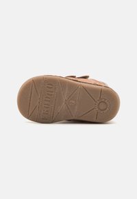 Semelle en caoutchouc brun avec un motif de grip texturé, présentant le nom de la marque « FRODDO » et le numéro de taille 19. Détail de bord doux et rembourré.