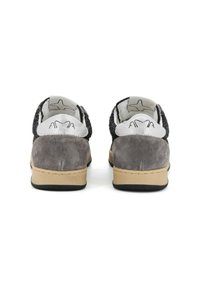 Un paio di sneaker in suede grigio e bianco con lati in maglia nera, suole beige e logo ricamato sul tallone, viste da dietro.