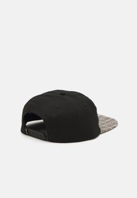 Juodas kepurė su tekstūruotu, raštuotu skutimu. Turi snapback uždarymą ir vėdinimo angas. Medžiaga atrodo kaip medvilnė ar panaši audinys.