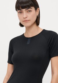 Zwarte short-sleeve top in een fitted ontwerp, gemaakt van zachte stof. Heeft een ronde halslijn en een subtiele logo-tag aan de voorkant.