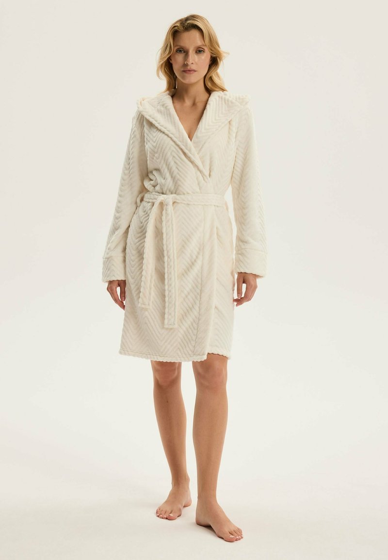 Biały, kapturowy szlafrok z fakturowanej tkaniny w jodełkę; związywany pasek w talii; długie rękawy; miękka struktura; sięga do połowy łydki.