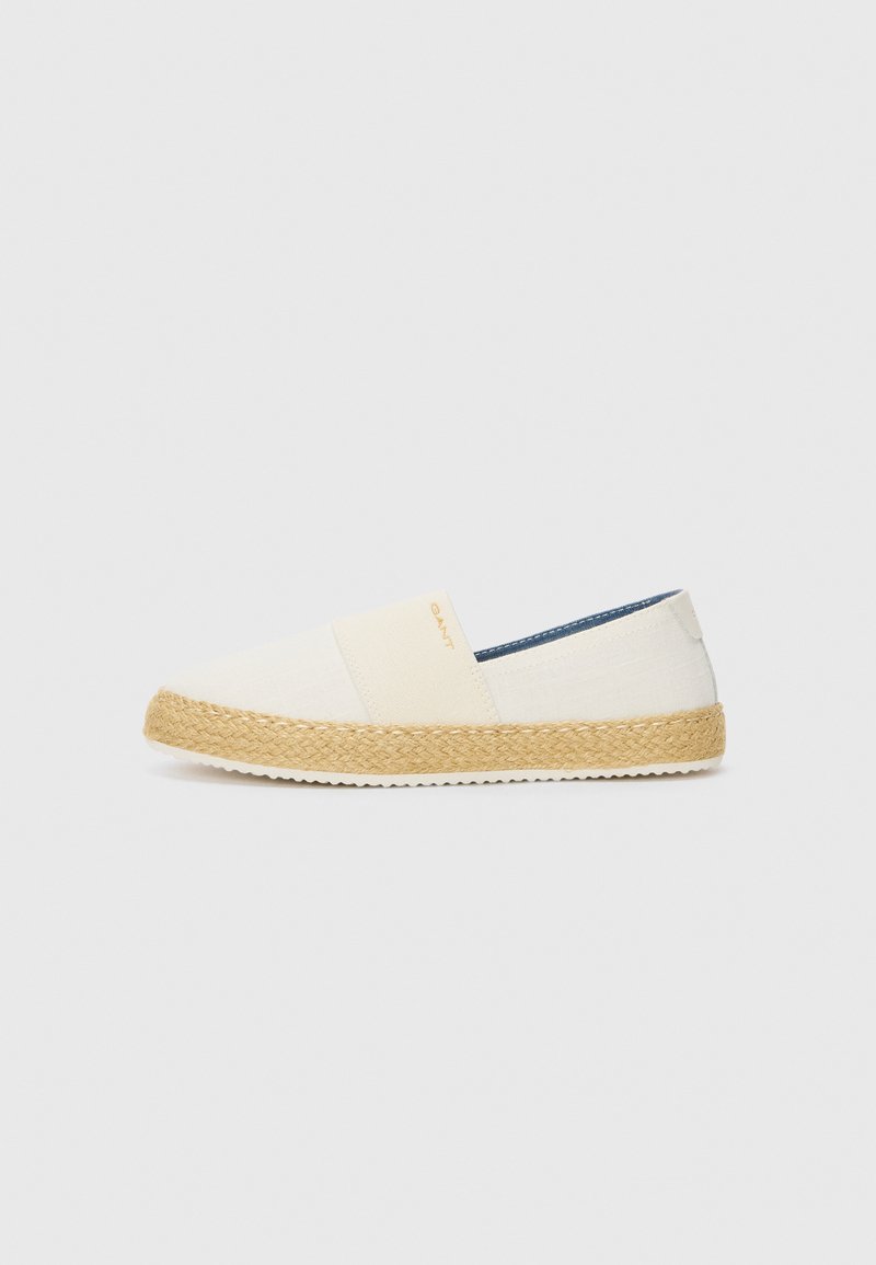 White canvas espadrille with a woven jute sole and elastic side panels; features a subtle logo on the side and a textured beige ribbon.