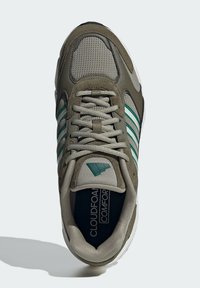 Maslinasto zelena tenisica sa mrežastim i antilop materijalima, tri tirkizne pruge, okrugli vezici i podstavljeni uložak označen "CLOUDFOAM COMFORT."