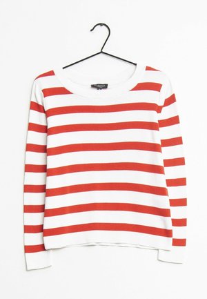 Pull à rayures rouges et blanches avec un col rond, des manches longues, une texture tricotée et une coupe décontractée, suspendu à un crochet noir.