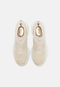 Beige slip-on sneakers med strikket overdel, ribbede detaljer og hvit såle. Har et gull merke på innersålen og en løkke for enkel påkledning.