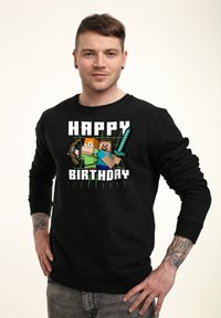 Felpa nera con grafica in pixel art che presenta personaggi e il testo "BUON COMPLEANNO". Vestibilità classica con maniche lunghe e polsini a costine.