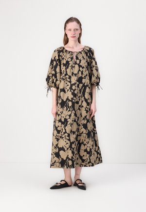 Svart og beige blomstermønstret kjole med pufferm, nøkkelhulln neckline og avslappet passform. Kombinert med svarte flate sko.
