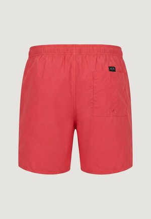 Bañador corto rojo para hombre con cintura elástica y un bolsillo trasero único que presenta un pequeño parche de logo negro en el lado derecho.