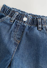 Blaue Denim-Hosen mit elastischem Bund, Gürtelschlaufen, vorderem Knopf und detaillierter oranger Naht auf hellem Hintergrund.