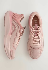 Des chaussures de sport rose clair avec une tige en mesh, des motifs texturés, des lacets plats et un col rembourré, dotées d'une semelle en caoutchouc cushonnée.