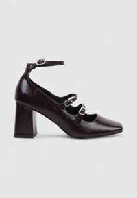 Chaussures à talons hauts en cuir verni brun foncé avec un bout carré, une bride à la cheville et deux accents de boucles ajustables. Design à talon carré.