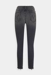 Jeans de denim negro con un corte slim, que cuentan con dos bolsillos traseros y dobladillos deshilachados. Desgaste sutil y costuras en zigzag en los bolsillos.