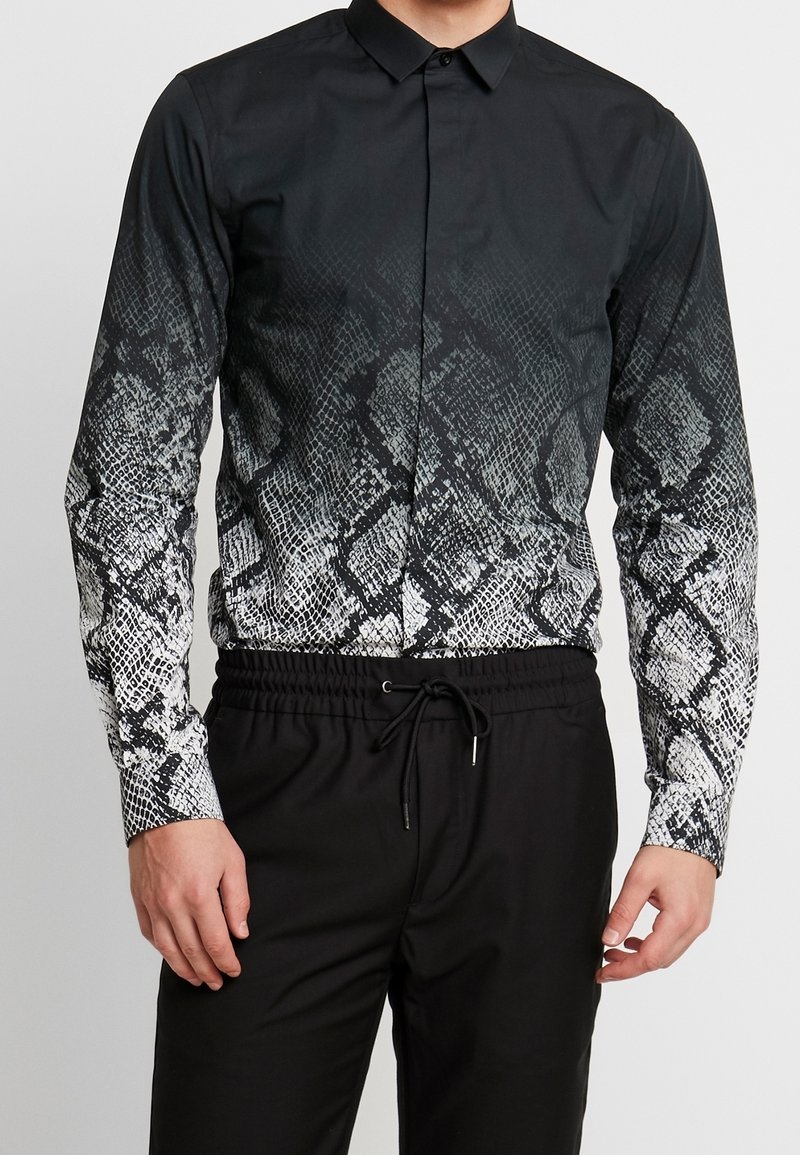 Black long-sleeve shirt with a snake print pattern transitioning from black to white. Features a button-down collar and slim fit. Paired with black pants.