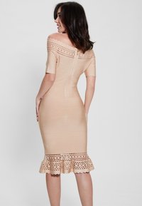 Nude bodycon suknelė su petnešėlėmis, tekstūruotas audinys, krokuota tekstūra ir banguotas kraštas. Uždarymas gale su užtrauktuku.