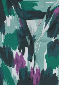 Camicia con bottoni caratterizzata da un motivo astratto multicolore nei toni del verde, viola e bianco, realizzata in un tessuto testurizzato e con bottoni neri.