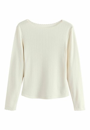 Long-sleeve top in cream, made of ribbed fabric with a textured pattern. Features a scalloped neckline and fitted design.