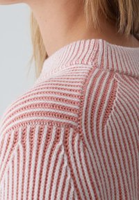 Pull en maille rose clair avec rayures blanches, doté d'un col côtelé et d'un motif texturé sur l'épaule.