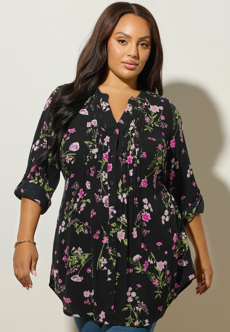 Blusa nera floreale con motivi di fiori rosa e verdi, chiusura con bottoni, pieghe e maniche arrotolate. Tessuto leggero con una vestibilità comoda.