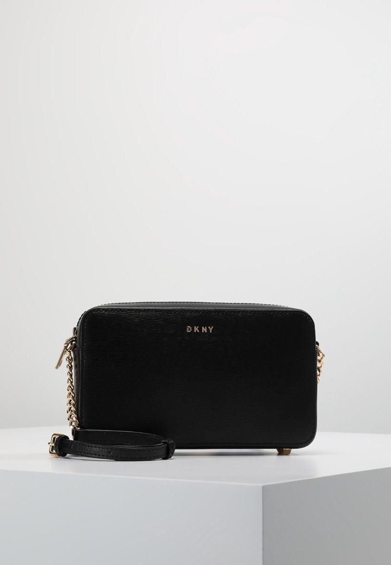 Czarna prostokątna torba na ramię wykonana z teksturowanego materiału, z złotym logo, łańcuszkiem i skórzanym paskiem oraz zamkiem błyskawicznym.