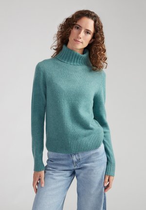Teal turtleneck sweater made of soft, knitted fabric with ribbed cuffs and hem, paired with light blue jeans.