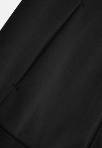 Tessuto di cotone nero con superficie liscia, dettagli di plissettatura strutturata e vita a coste. Adatto per l'abbigliamento casual.