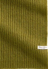 Olivgrüner gerippter Strickschal mit strukturierter Oberfläche, versehen mit einem kleinen weißen Markenlabel, das am Rand angenäht ist.