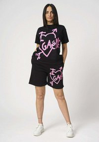 Set di maglietta nera e pantaloni corti in cotone, con testo grafico e design a cuore rosa. Maniche corte e tasche sui pantaloni corti.