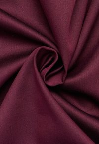 Bordeaux stof met een gladde textuur, licht glanzend oppervlak en een diagonale ribbelpatroon, gerangschikt in een spiraalvormige plooi.