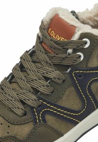 Dunkelgrüner Sneaker mit Schnürdesign, Futter aus Kunstfell, gemusterten Schnürsenkeln, gelben Nähten und einem braunen Lederschild mit der Aufschrift "S. OLIVER".