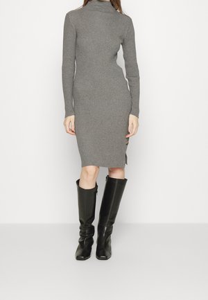 Robe en maille gris côtelé, cintrée, à manches longues et col haut, associée à des bottes en cuir noires montantes jusqu'aux genoux.