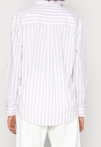 Chemise à manches longues rayée violet clair et blanc, dotée d'un col à boutons, d'un ourlet incurvé et de poignets boutonnés.