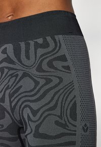 Black textured leggings featuring a wavy pattern and mesh detailing along the side. Material appears stretchy and form-fitting.