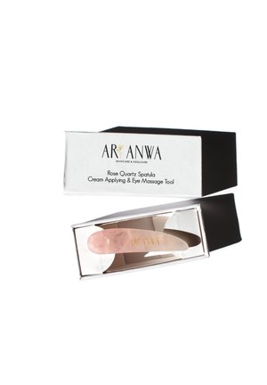 Rose quartz spatula with a smooth, pale pink surface, housed in a black-and-white box featuring gold text for branding and product details.