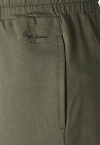 Spodnie dresowe z bawełny w oliwkowym zielonym kolorze, z elastycznym pasem, boczną kieszenią oraz wyszywanym logo "Pepe Jeans London". Gładka faktura, casualowy design.