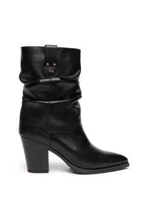 Botte mi-mollet en cuir noir avec tige souple, talon bloc, bout pointu et détail du logo métallique près du haut.