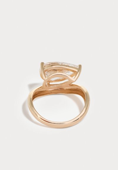 Inel de aur cu o piatră prețioasă mare, clară și tăiată în fațete, așezată într-o montură rotundă ridicată cu patru gheare, pe o bandă simplă, pe fundal alb.