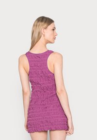 Vestido roxo sem mangas com textura plissada, corpete ajustado e bainha em formato de ondas. Apresenta um decote redondo e um tecido suave e elástico.