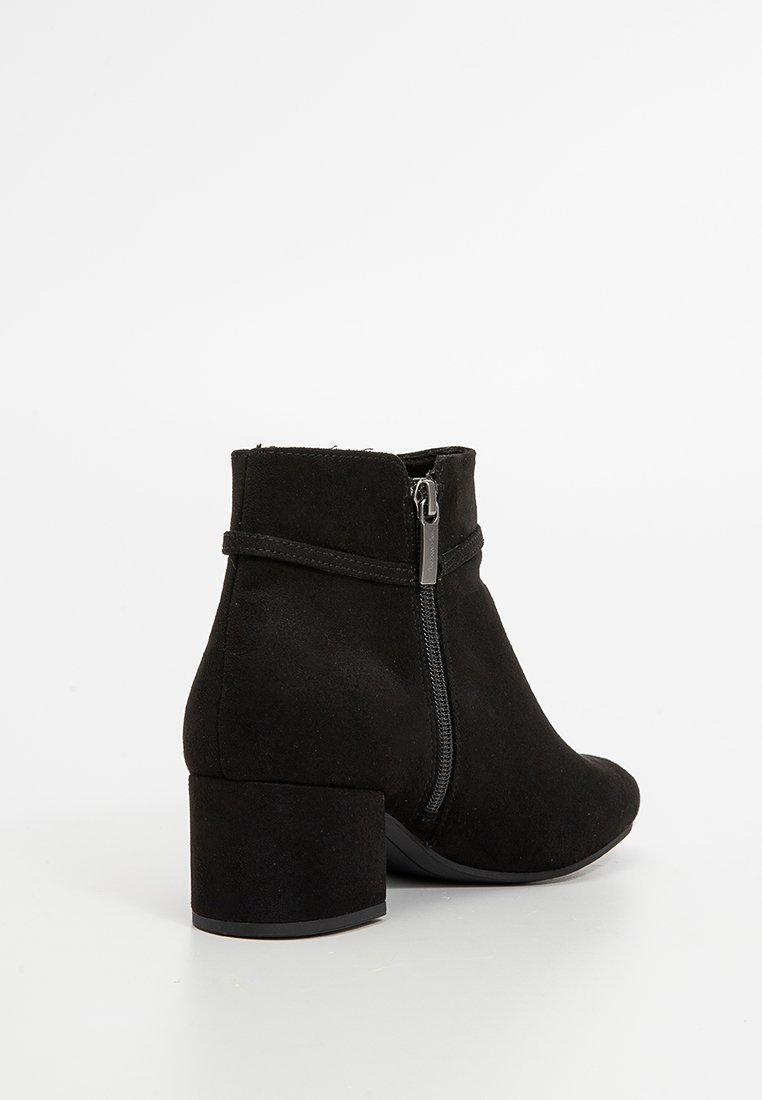 Bottine en suède noir avec un bout arrondi, un petit talon carré, une fermeture éclair sur le côté et un design minimaliste. Texture lisse, sans motifs visibles.